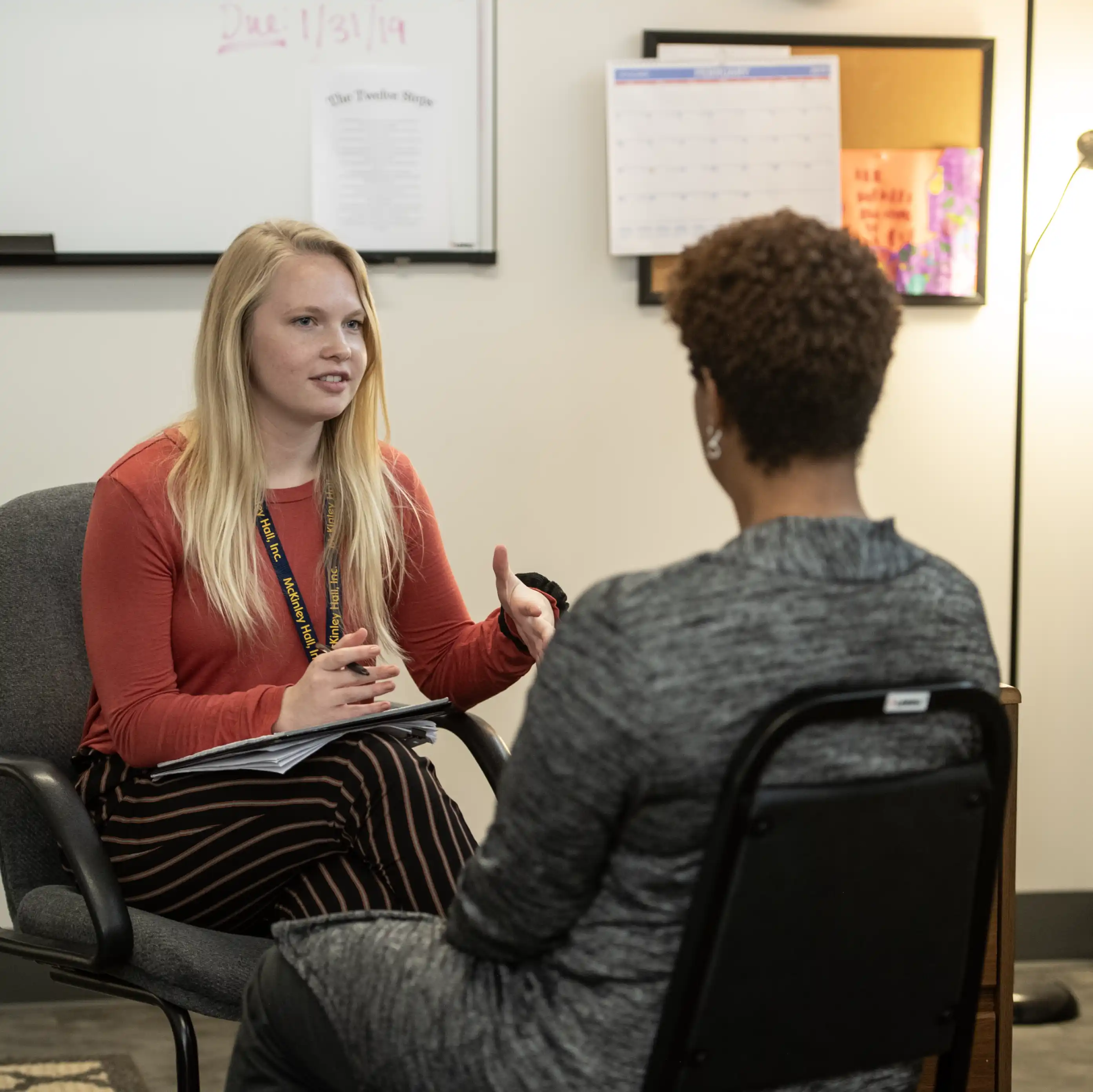 Two females seated discussing an issue.