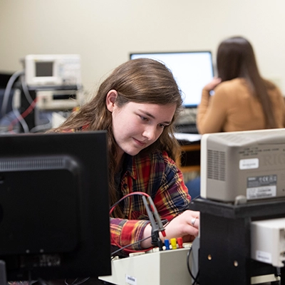 Female student working with electronics gear. with