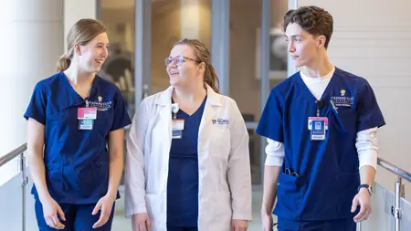 Female faculty discussing something with two nursing students.