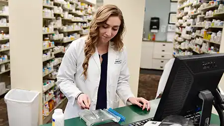 Pharmacist preparing a prescription at the counter in a pharmacy.