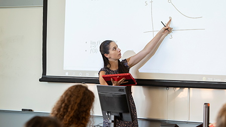Professor at the front of a classroom teaching calculus equations.