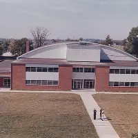 Three people standing in front of gymnasium building.