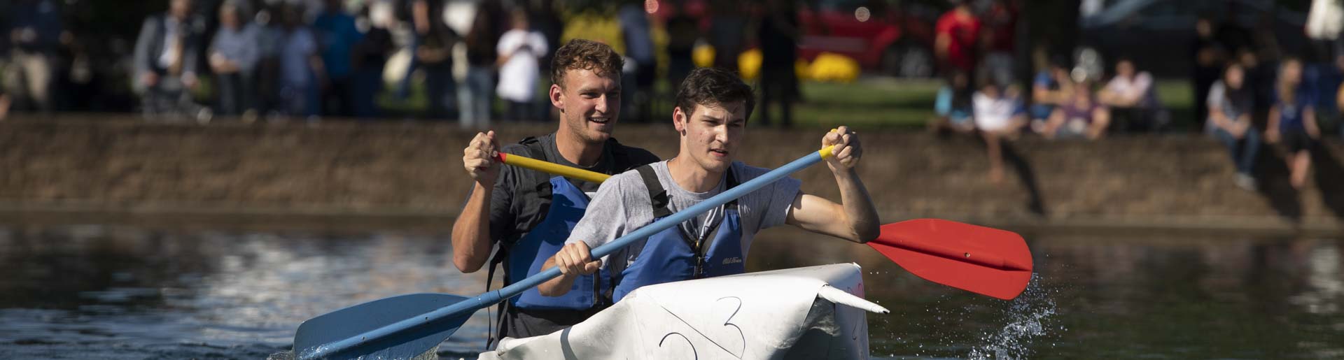 Students racing across Cedar Lake in a cardboard canoe
