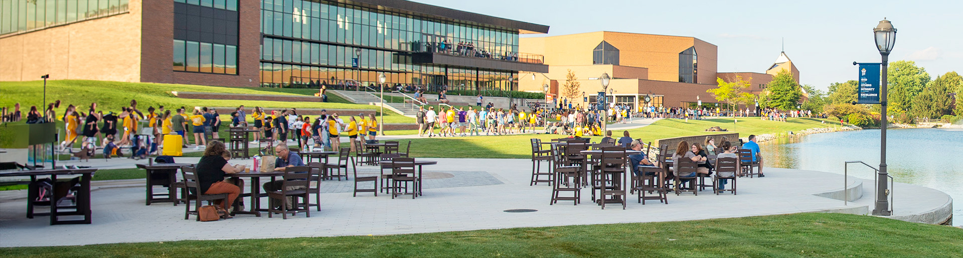 A view of the Scharnberg Business and Communication Center from the lake with students milling about during Getting Started Weekend