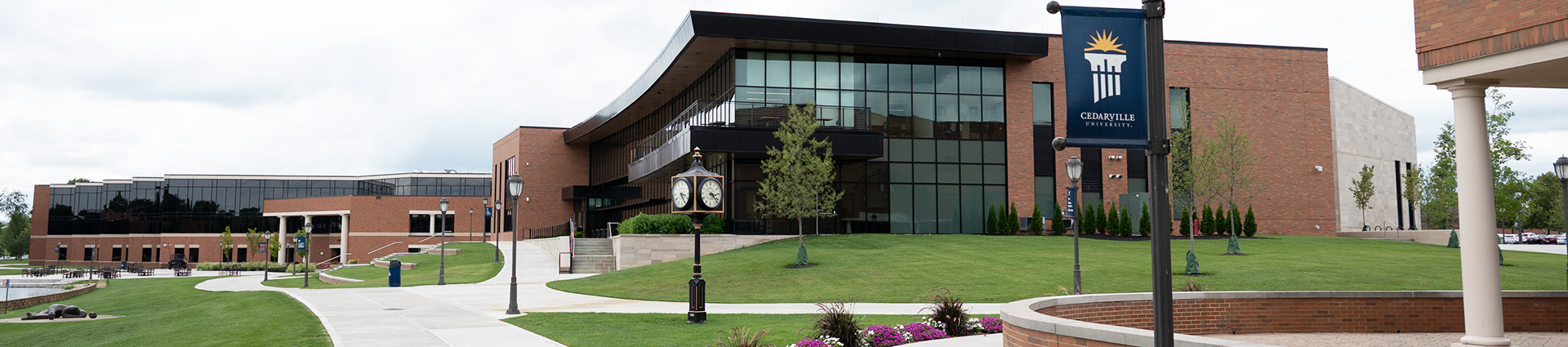 The Scharnberg Business and Communication Center with campus clock and torch banner in foreground.