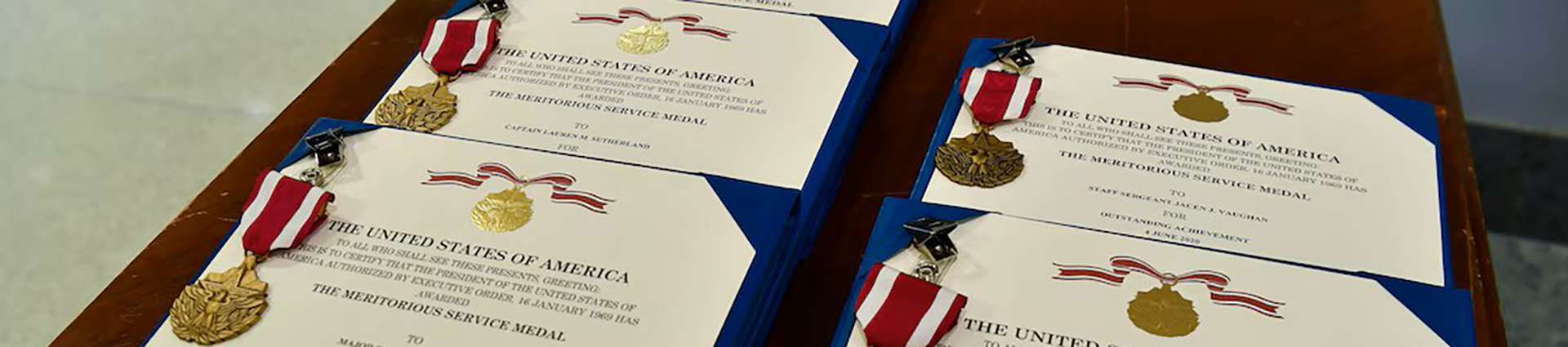 Meritorious service medals and certificates on a table.