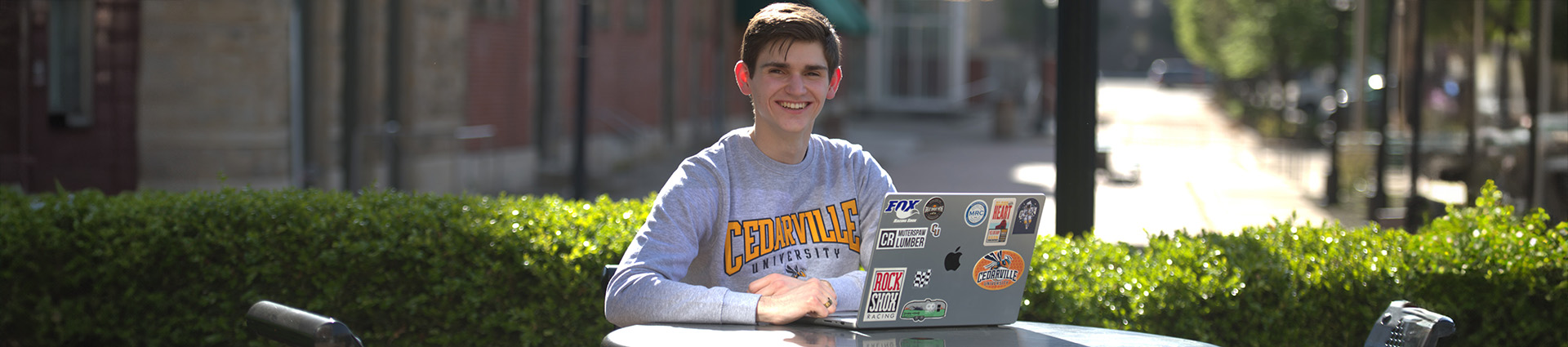 Zach Erway sits at an outdoor table with his laptop.