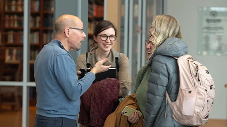 Professor talking to three college students in academic building