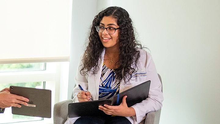 Woman in white coat taking notes.