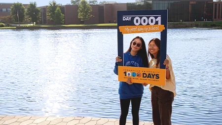 Three female students talking and laughing while walking down campus sidewalk