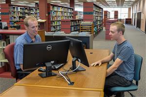 Students sitting at a desk working on computers