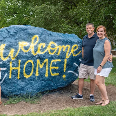 Parents smiling by rock that says 
