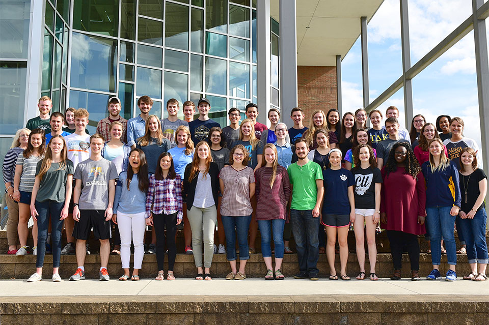 Group picture of dozens of student tutors outside on the BTS Center stairs on sunny day.