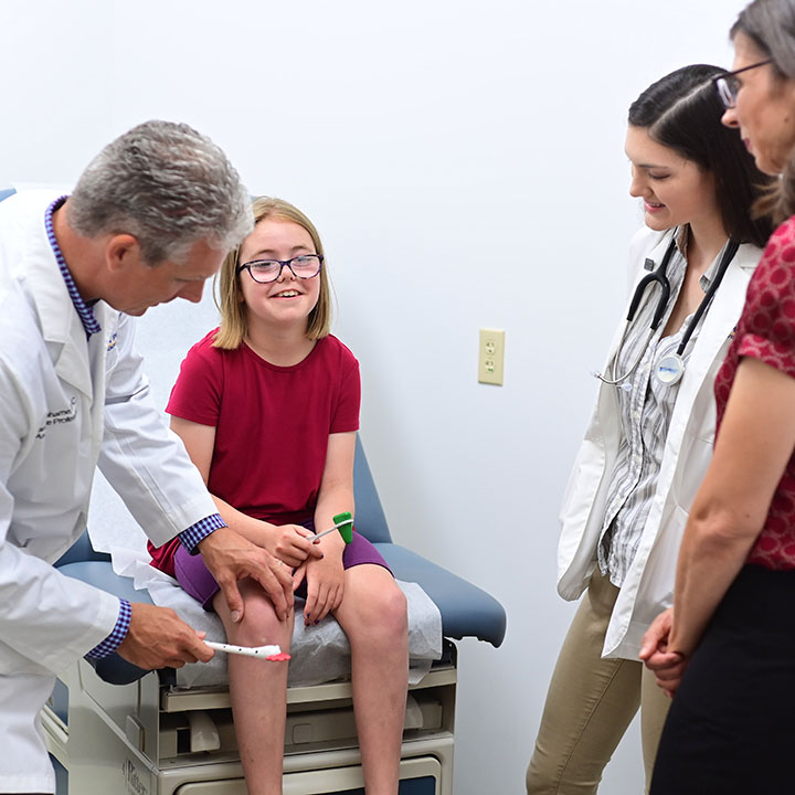 Physician Assistant providing care for a youth in a medical office.