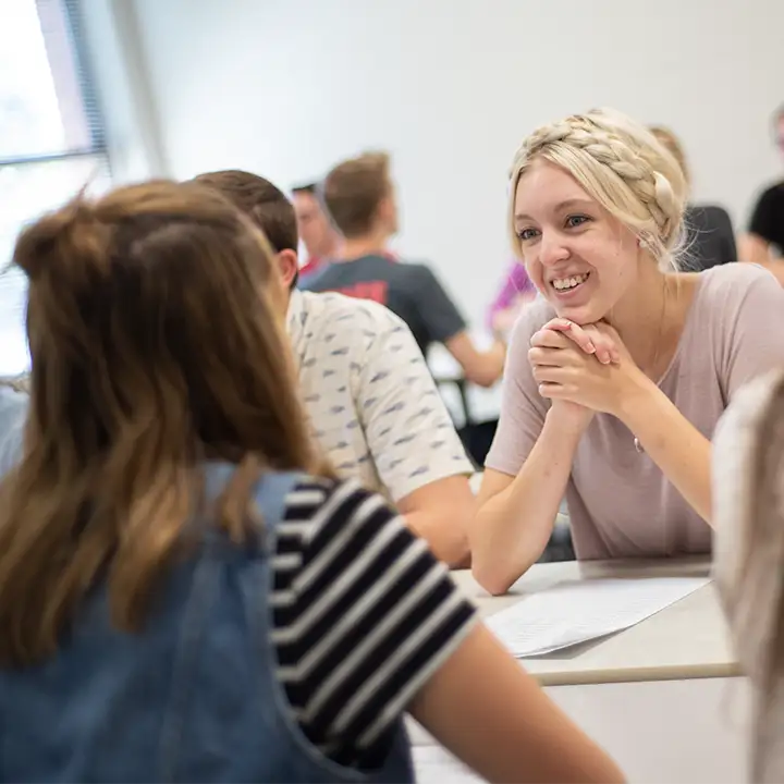 Woman smiling in room full of people.