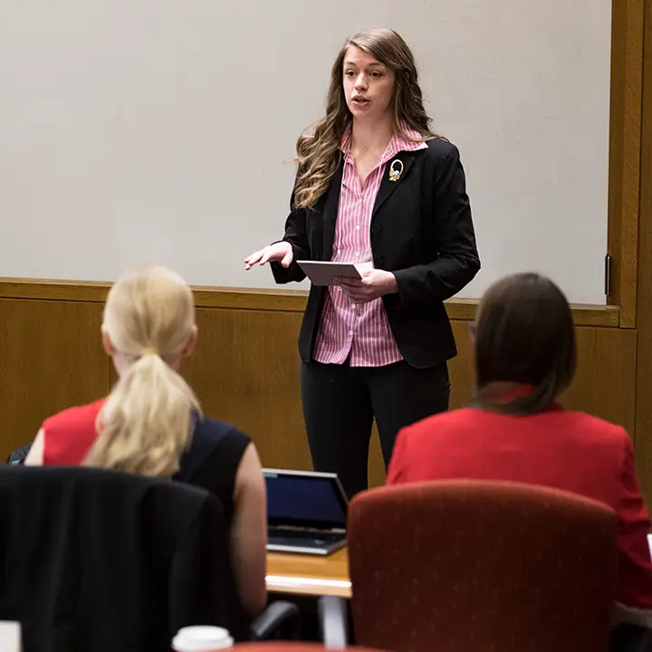 Woman speaking in front of a classroom.