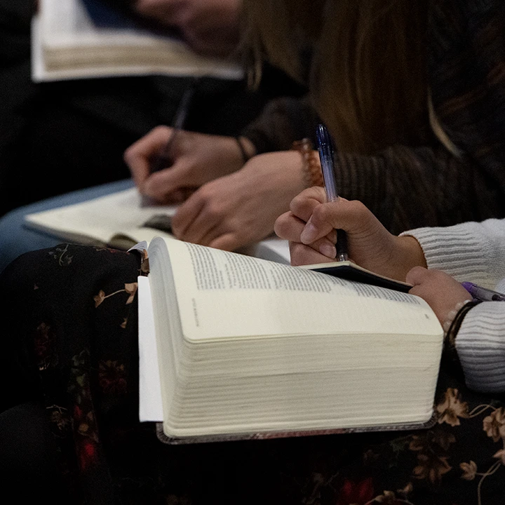 Taking notes next to an open Bible.