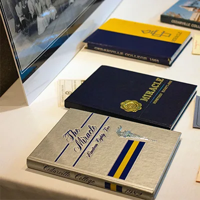 Four historical Cedarville College yearbooks displayed on table.