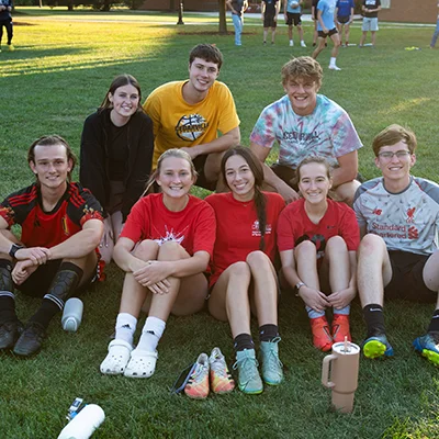 Students smiling outside and resting from soccer game.