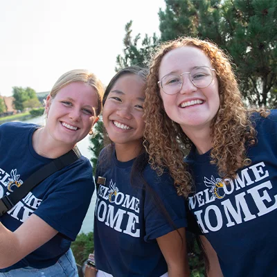 Three college students in Welcome Home shirts.